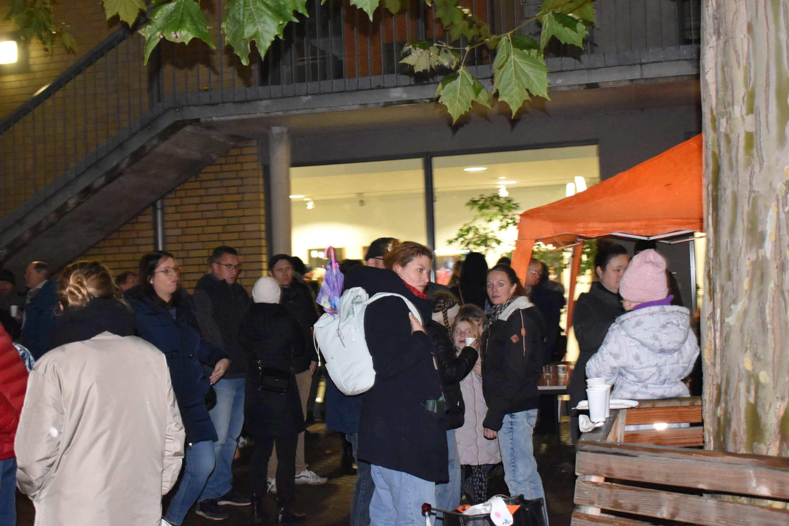 Gruppe von Menschen bei einem nächtlichen Markt, mit freundlichen Ausdruck, Herbstfarben, buntes Zelt.