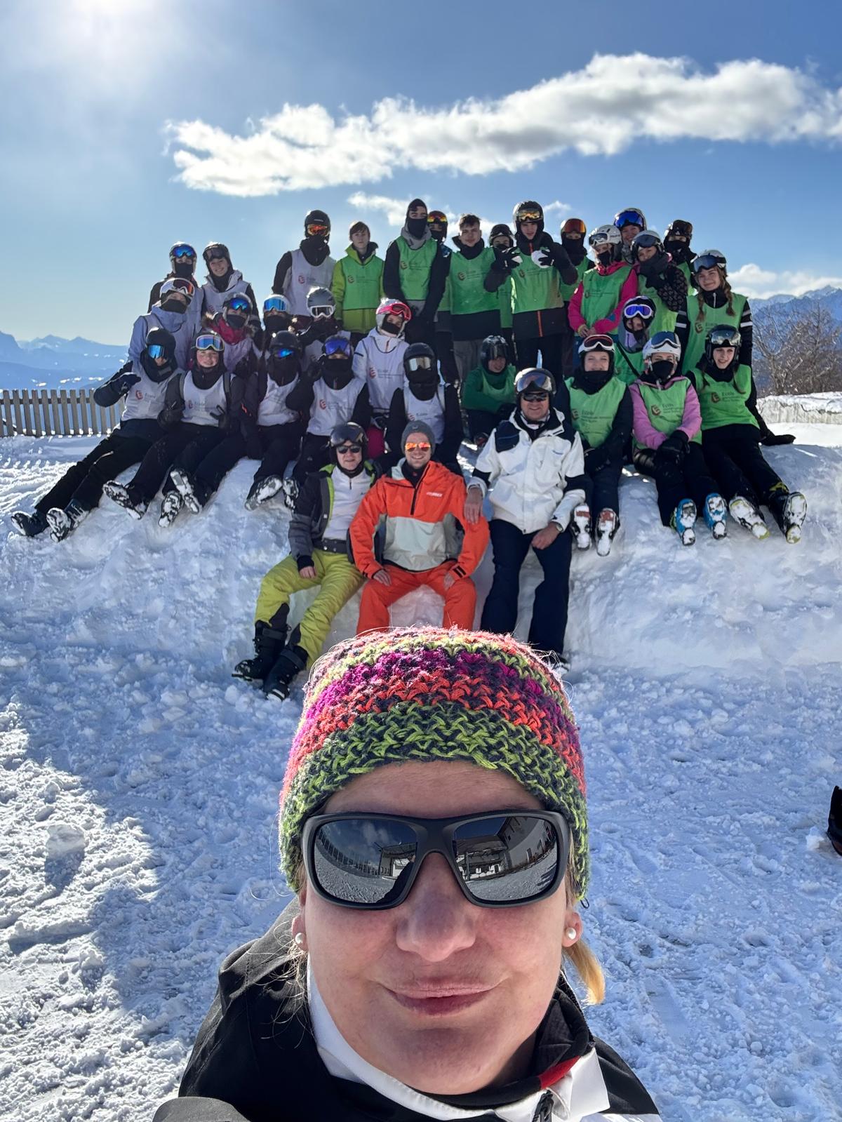 Gruppe von Skifahrern und Skifahrerinnen in Winterkleidung posiert lächelnd im Schnee.